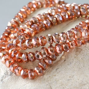 May include: A strand of copper-colored glass beads with a faceted finish. The beads are strung together in a long, continuous strand.