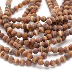 May include: A strand of brown and white banded agate beads. The beads are round and have a matte finish.