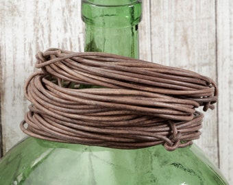 May include: A green glass bottle with a brown leather wrap around the neck.