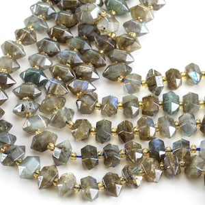 May include: A strand of faceted labradorite gemstone beads with a gold-toned metal spacer between each bead. The beads are a dark gray with iridescent blue and green flashes.