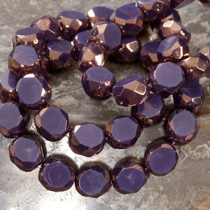May include: A strand of purple glass beads with a copper metallic finish. The beads are faceted and have a rounded, octagonal shape.