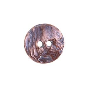May include: A round, textured button with two holes. The button has a mottled appearance with shades of brown, purple, and copper. The button is likely made of metal and has a rustic, weathered look.