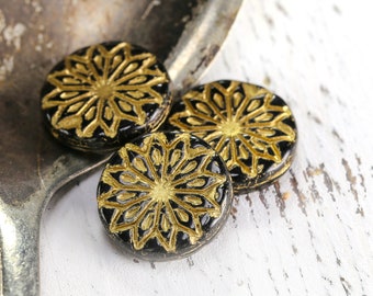 May include: Three black and gold round buttons with a decorative snowflake design.