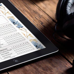 May include: A black tablet displaying an "ADHD Daily Planner" with checkboxes and sections for scheduling. Headphones and a sound mixer are on a wooden surface. The planner has floral accents.