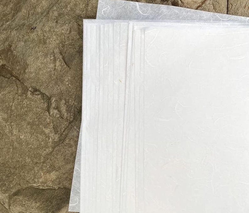 May include: A stack of white textured paper sheets. The paper has a slightly rough, handmade look.