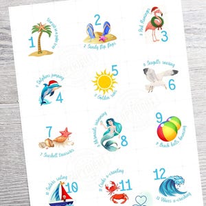 Peut inclure: Une impression blanche avec des illustrations colorées sur le thème de la plage. Comprend un palmier, des tongs, un flamant rose, des dauphins, un soleil, des mouettes, des coquillages, une sirène, des ballons de plage, un voilier, des crabes et des vagues. Texte : "Down South Artisans".