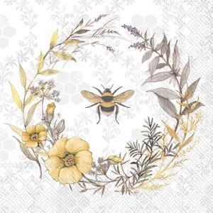 May include: A decorative paper napkin featuring a watercolor illustration of a bumblebee surrounded by a floral wreath. The wreath includes yellow flowers, lavender, and various green and gray leaves, set against a white background with a subtle pattern.
