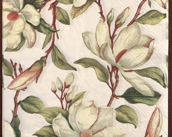 Puede incluir: Una servilleta de papel rectangular con un patrón botánico repetitivo de flores de magnolia blancas con centros crema, hojas de color verde oscuro y ramas marrones sobre un fondo blanco puro con una sutil textura en relieve.