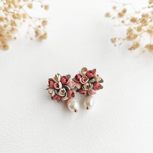 May include: A pair of floral earrings with pink, white, and green polymer clay flowers and a pearl dangle.