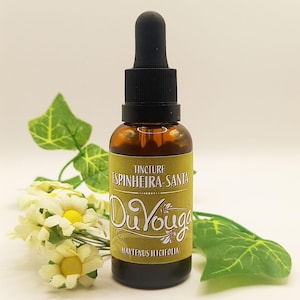 Op de afbeelding: Een bruine glazen tinctuurfles met een zwarte druppelaar en een geel etiket. Op het etiket staat "Tincture Espinheira-Santa Du Youga Maytenus Ilicifolia" in een decoratief lettertype. De fles is omgeven door witte bloemen en groene bladeren.