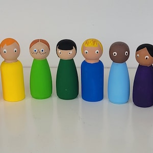 Könnte beinhalten: Ein Set mit 13 Holz-Steckpuppen, die in verschiedenen Farben des Regenbogens bemalt sind. Jede Puppe hat ein einzigartiges Gesicht und eine einzigartige Frisur.