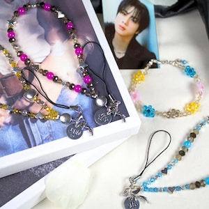 May include: Several beaded phone charms in various colors, including yellow, pink, and blue. Each charm features a different design, with some incorporating star and heart-shaped beads. The charms have silver-toned metal accents.