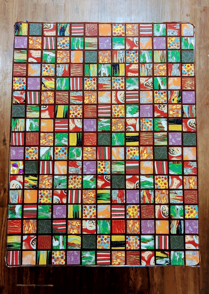May include: A square table top with a mosaic design. The mosaic is made up of small squares of different colors and patterns, including red, green, yellow, orange, and purple. The table top is made of wood and has a dark brown finish.