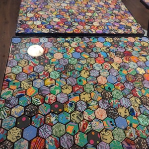 May include: Two square tables with black legs and a hexagonal mosaic top. The mosaic is made of colorful, patterned tiles with gold accents.