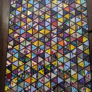 May include: A table top with a geometric pattern of colorful triangles. The triangles are made of different fabrics and patterns, creating a vibrant and eclectic design.