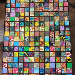 May include: A colorful mosaic table top with a grid pattern of small squares. Each square is filled with a different pattern of colorful swirls and designs.