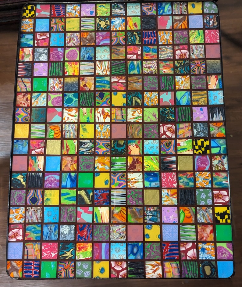 May include: A colorful mosaic table top with a grid pattern of small squares. Each square is filled with a different pattern of colorful swirls and designs.