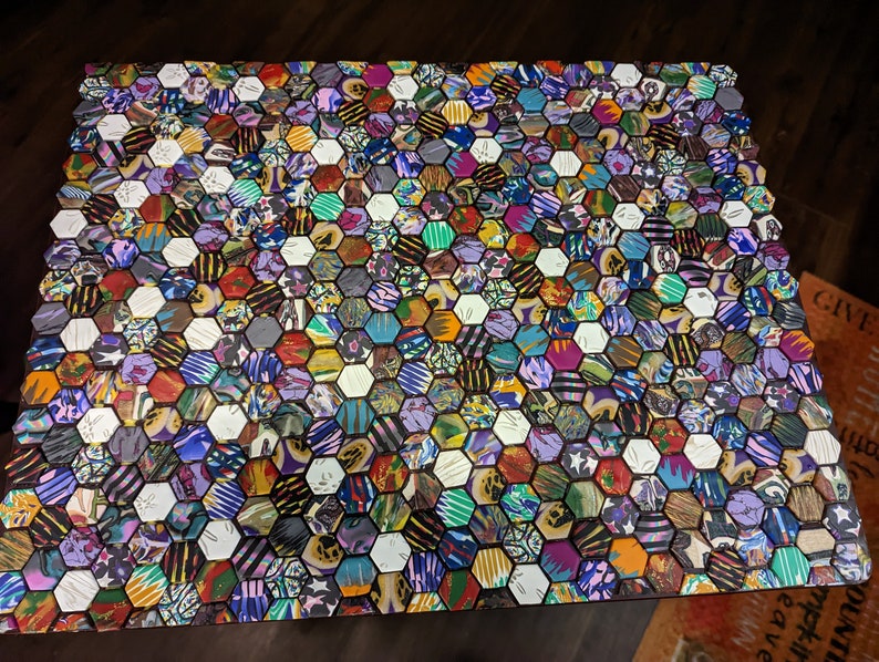 May include: A table top covered in a colorful hexagonal mosaic tile pattern. The tiles are made of various materials and have different patterns and colors, including purple, blue, green, yellow, red, and black.