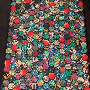 May include: A colorful table top with a hexagonal pattern. The table top is made of many different colors and patterns, including red, green, blue, and yellow. The hexagonal pattern is made of small squares and rectangles.
