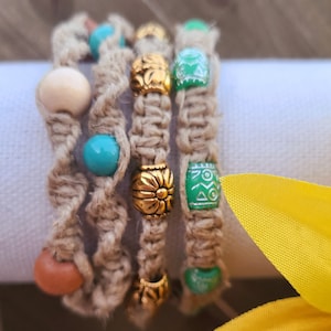 May include: Four hemp bracelets with colorful beads. The bracelets are made with natural hemp cord and feature turquoise, green, and brown beads. The beads have a variety of patterns and designs.