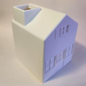May include: A white, miniature house model with a chimney and windows. The house has a gabled roof and a rectangular body. The windows and door are cut out of the house's side. The chimney is a small, rectangular shape.