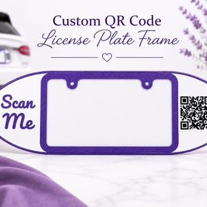 May include: A white and purple license plate frame featuring a rectangular center cutout, the text Scan Me in purple script on the left side, and a black and white QR code on the right side. The frame has a smooth finish and rounded edges.