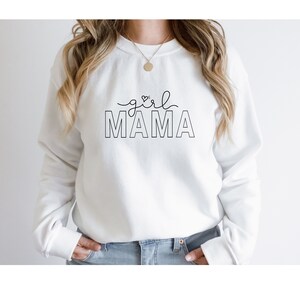 Peut inclure: Sweat-shirt blanc avec le texte "girl mama" en lettres noires. Le texte est soulign&eacute; en noir et le mot "girl" a un petit c&oelig;ur au-dessus.