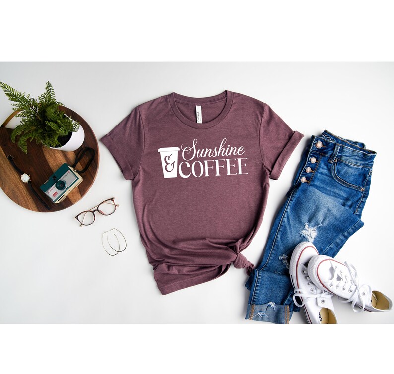 May include: A maroon t-shirt with white text that reads "Sunshine & COFFEE" and a white graphic of a coffee cup.