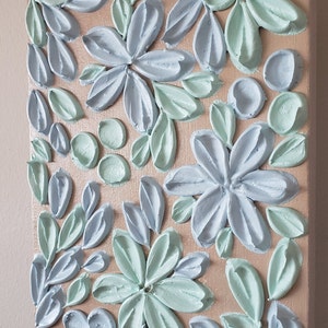 May include: A square canvas painting with a textured, raised paint design. The painting features a floral pattern with blue and green flowers and leaves.