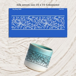 Puede incluir: Un esténcil de serigrafía azul con un diseño floral y de pájaros blanco, que mide 22 x 11 centímetros. También se muestra una taza de cerámica con un diseño similar. El texto "Silk screen size 22 x 11 Centimeter" es visible.