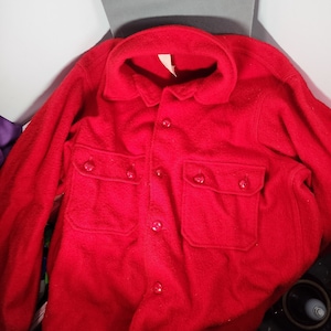 May include: A red long-sleeved button-up shirt with two flap pockets and a collar.