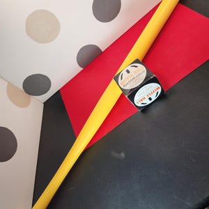 May include: A yellow plastic wiffle ball bat with a black and white box of wiffle balls. The box says "Wiffle Ball" and "Regulation Size".