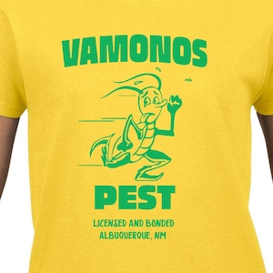 Może przedstawiać: Żółta koszulka z zielonym, kreskowym karaluchem biegnącym i tekstem "VAMONOS PEST LICENSED AND BONDED ALBUQUERQUE, NM"