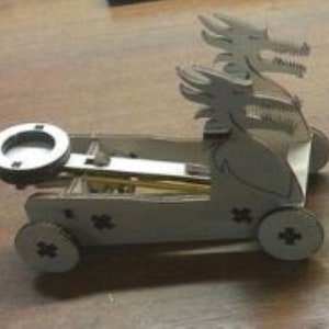 Puede incluir: Un juguete de dragón de madera blanco con un mecanismo de retroceso. El dragón tiene dos cabezas y está sobre una base de madera con ruedas. El juguete está diseñado para ser tirado hacia atrás y luego soltado, lo que hace que se mueva hacia adelante.