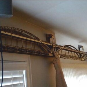 May include: A wooden model of a bridge, with multiple arches, is mounted on a wall. The model is made of light brown wood and appears to be a detailed replica of a real bridge.
