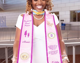Puede incluir: Una estola de graduación rosa y morada con el nombre "Darshanay Renee Pichon" y el texto "This one is for Alonnie". La estola también presenta un sello con el texto "University of Missouri - St. Louis" y una cita de la Biblia: "Bienaventurada la que creyó que se cumplirían las palabras que le fueron dichas de parte del Señor - Lucas 1:45".