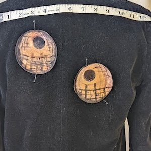 May include: Black velvet jacket with two round, brown and black, decorative patches sewn on the back. The patches have a geometric design.