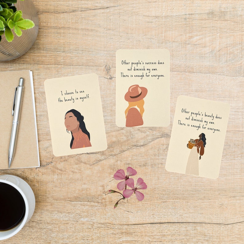 May include: Three affirmation cards with illustrations of women and text that reads: "I choose to see the beauty in myself."  "Other people's success does not diminish my own. There is enough for everyone."  "Other people's beauty does not diminish my own. There is enough for everyone."
