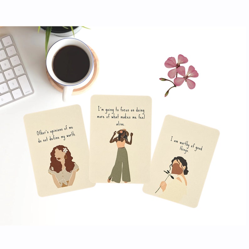May include: Three affirmation cards with illustrations of women and inspirational messages. The cards are beige with brown text. The first card says "Other's opinions of me do not define my worth." The second card says "I'm going to focus on doing more of what makes me feel alive." The third card says "I am worthy of good things."