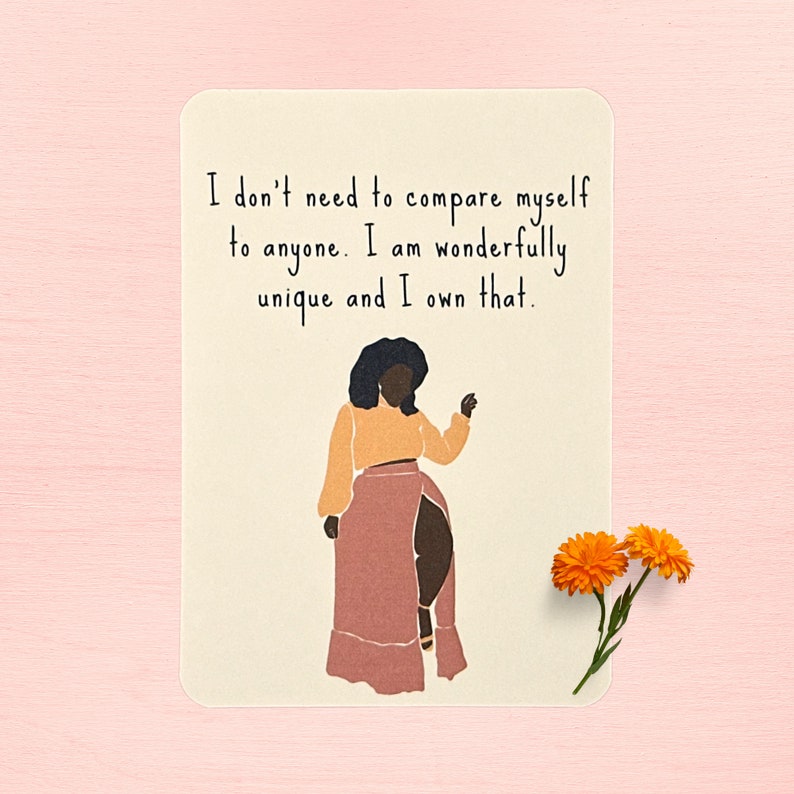 May include: A beige card with a black and brown illustration of a woman with a quote that reads "I don't need to compare myself to anyone. I am wonderfully unique and I own that."