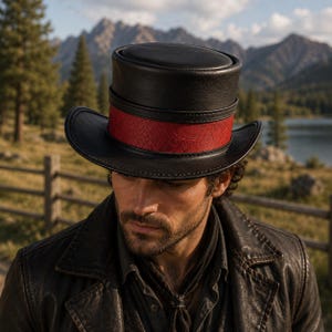 May include: A black leather top hat featuring a flat crown and a wide, curved brim. A vibrant red band with a subtle, repeating geometric pattern encircles the base of the crown, providing a distinct contrast against the smooth black leather material.