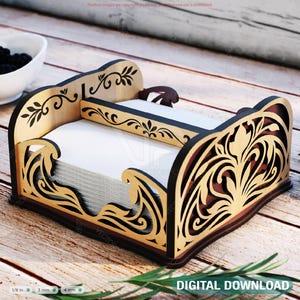 May include: A decorative wooden napkin holder with intricate cut-out designs. The holder features a light brown and dark brown color scheme with floral and wave-like patterns. The holder is filled with white napkins and sits on a wooden surface. The text "DIGITAL DOWNLOAD" is visible.