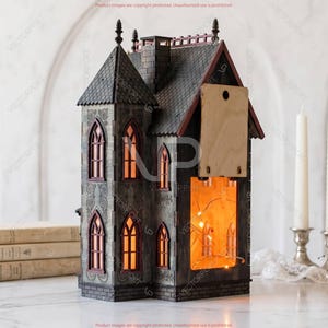 May include: A decorative, gray and red miniature haunted house with illuminated windows. The house features a detailed facade with arched windows and a wooden back panel. The interior glows with warm light, suggesting a cozy ambiance. The house is a unique Halloween or holiday decoration.