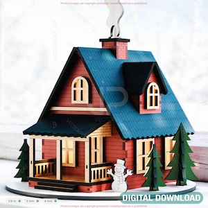 May include: A miniature wooden house with a red exterior, blue roof, and black trim. The house features a chimney with smoke, a porch, and two green trees. A snowman is in front of the house. The text "DIGITAL DOWNLOAD" is at the bottom.