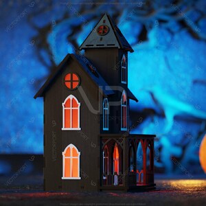 May include: A dark wooden haunted house with glowing windows sits in front of a blue and black background. A large orange pumpkin sits to the right of the house.