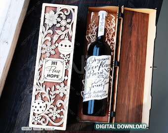 May include: A wooden wine box with intricate laser-cut designs of snowflakes, ornaments, and floral patterns. The box contains a bottle of wine with a label that reads "Organic Elderflower Presse". The words "Joy, Peace, Hope" are also visible.