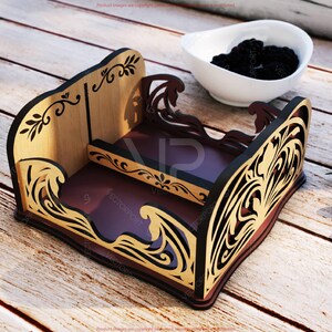 Pu&ograve; includere: Un vassoio in legno decorativo a pi&ugrave; livelli con base marrone scuro e lati marrone chiaro. Il vassoio presenta intricati disegni ritagliati con un motivo a vortice e accenti floreali. Una ciotola bianca piena di bacche scure &egrave; sullo sfondo.