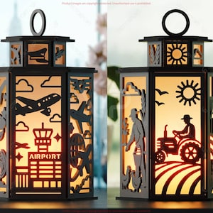 May include: Two black metal lanterns with cut-out designs. One features an airport scene with airplanes and the word "AIRPORT." The other depicts a farmer on a tractor and a rural landscape. Both have a warm, glowing interior.