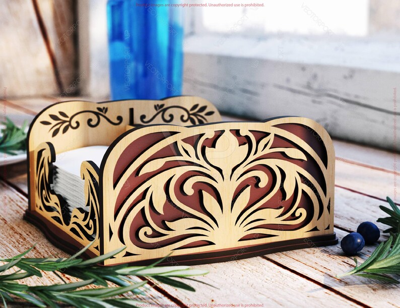 Pu&ograve; includere: Porta tovaglioli in legno con intricati ritagli floreali. Il supporto presenta un esterno marrone chiaro e un interno marrone scuro, e contiene una pila di tovaglioli bianchi. Il design include motivi decorativi di foglie e volute.