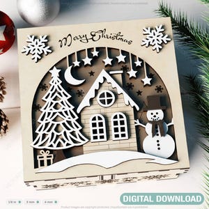 Könnte beinhalten: Eine hölzerne Weihnachtsbox mit einem ausgeschnittenen Design eines Hauses, eines Schneemanns, eines Weihnachtsbaums und Sternen. Die Box trägt den Schriftzug "Merry Christmas" auf der Vorderseite.